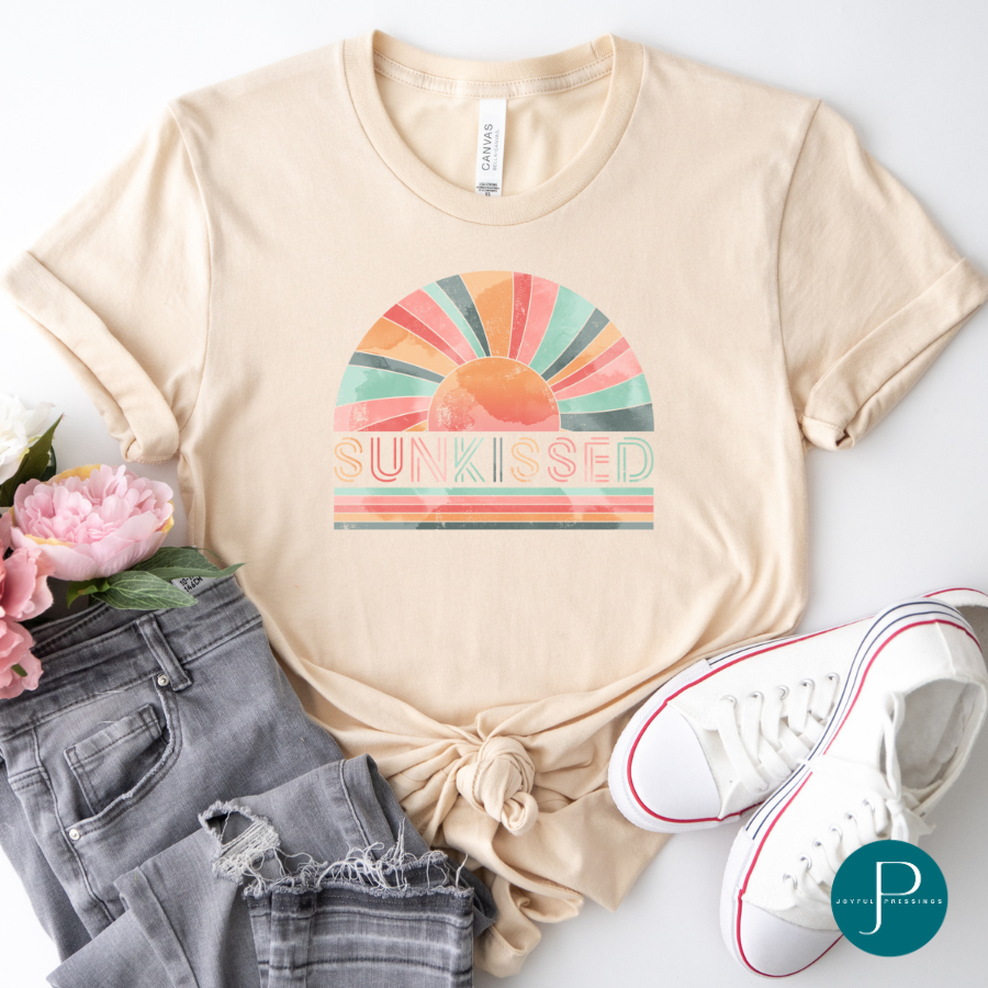 pink, teal and orange "sunkissed" print on a tan tee