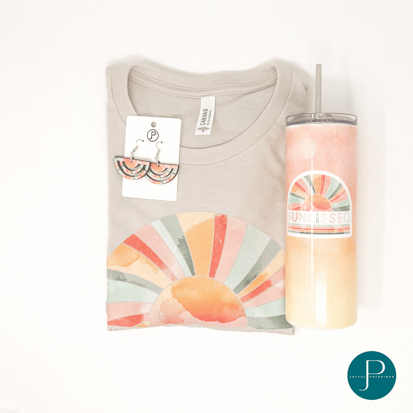 pink, teal and orange "sunkissed" print on a tan tee paired with matching earrings and tumbler