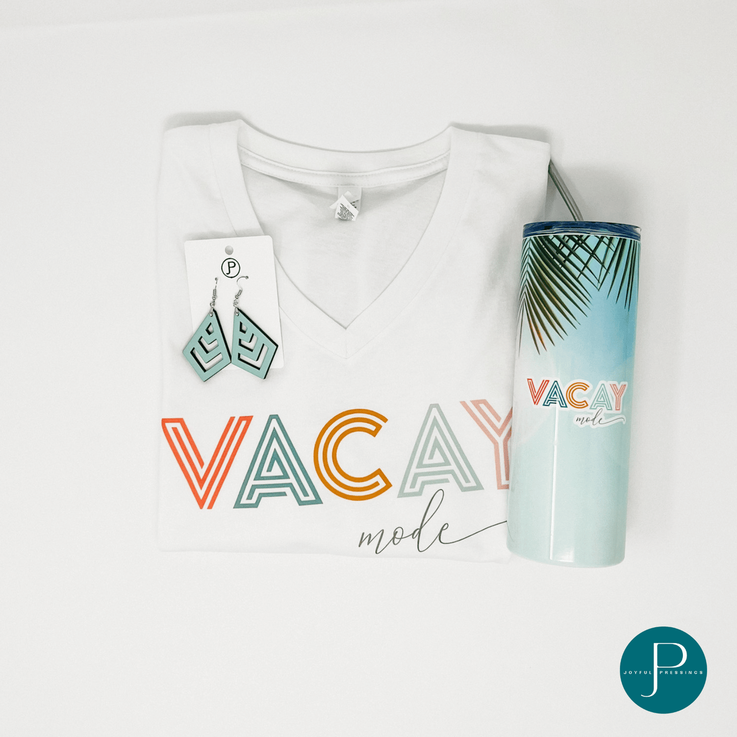 v-neck white tee with the print "vacay mode" printed in coral, blue, orange, and pink paired with matching earrings and tumbler
