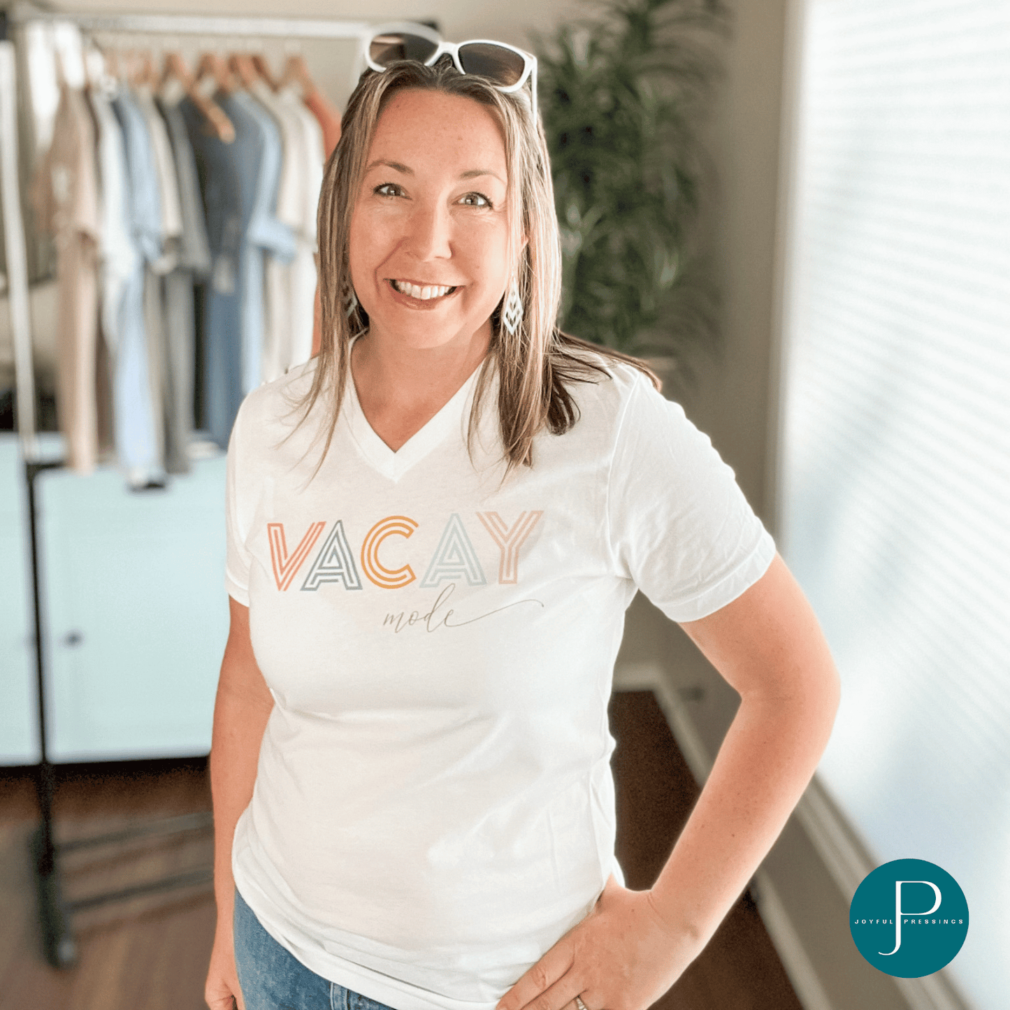 model showcasing a v-neck white tee with the print "vacay mode" printed in coral, blue, orange, and pink