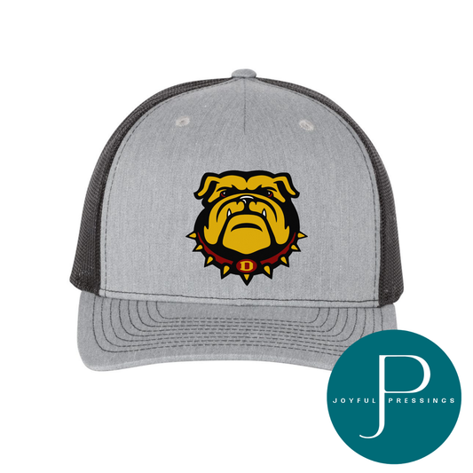 A heather gray and black trucker hat featuring a yellow bulldog mascot logo with a red collar and the letter 'D' on the front. A teal circular 'Joyful Pressings' brand watermark is visible in the bottom right corner.