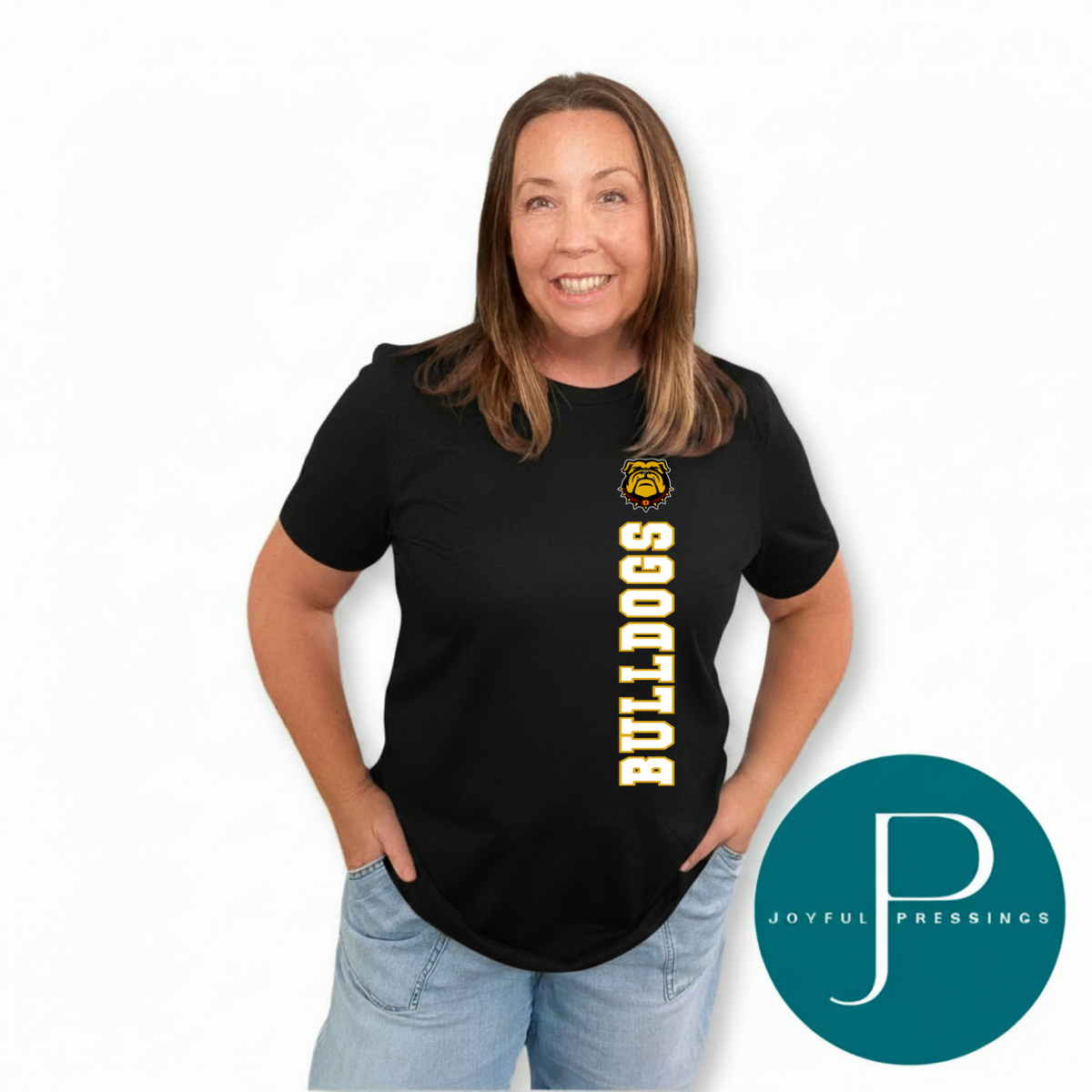 A woman wearing a black short-sleeve t-shirt with 'BULLDOGS' printed vertically in yellow and a bulldog mascot logo on the chest, paired with light blue jeans. A teal circular logo for 'JOYFUL PRESSINGS' is in the bottom right corner against a white background.