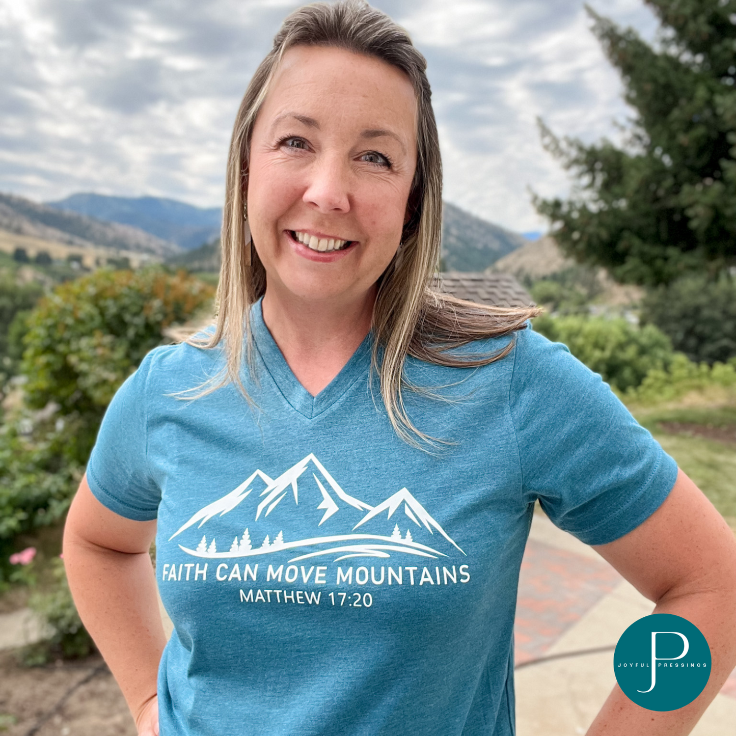 model wearing faith can move mountains print on a deep teal t-shirt