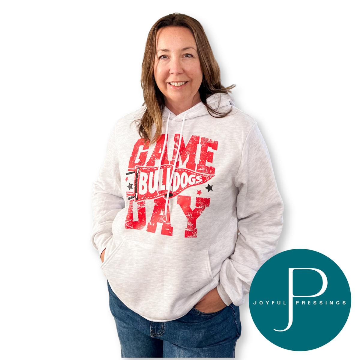 Woman smiling in an ash Game Day Bulldogs hoodie with a distressed red Bulldogs pennant design, paired with jeans