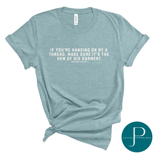 mockup of Hanging on by a thread blue lagoon t-shirt with cream print.