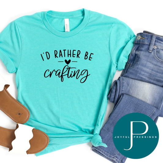 Heather sea green crew neck t-shirt with the phrase ‘I’d Rather Be Crafting’ styled with jeans and sandals.