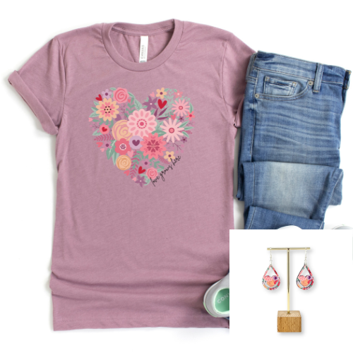 A mauve pink short-sleeve t-shirt with a colorful heart-shaped floral graphic and the text 'love you 2016' on the front, styled with blue jeans and a pair of dangling earrings on a white background.