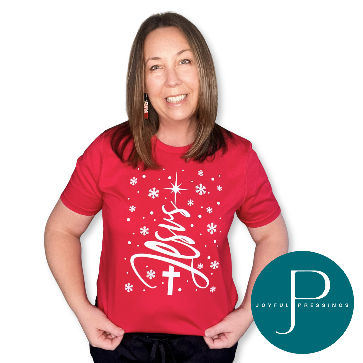 Woman wearing a red Bella + Canvas t-shirt with a white “Jesus” Christmas tree design featuring a cross, star, and snowflakes.