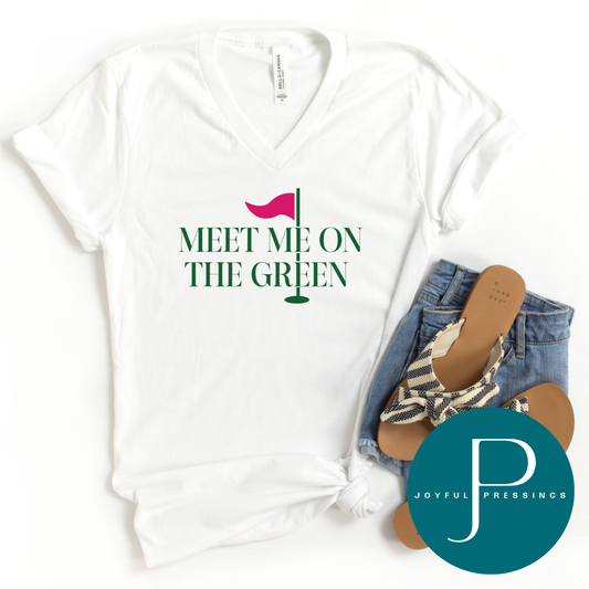 White v-neck t-shirt with “Meet Me On the Green” golf design styled with denim shorts, sandals, and Joyful Pressings logo.