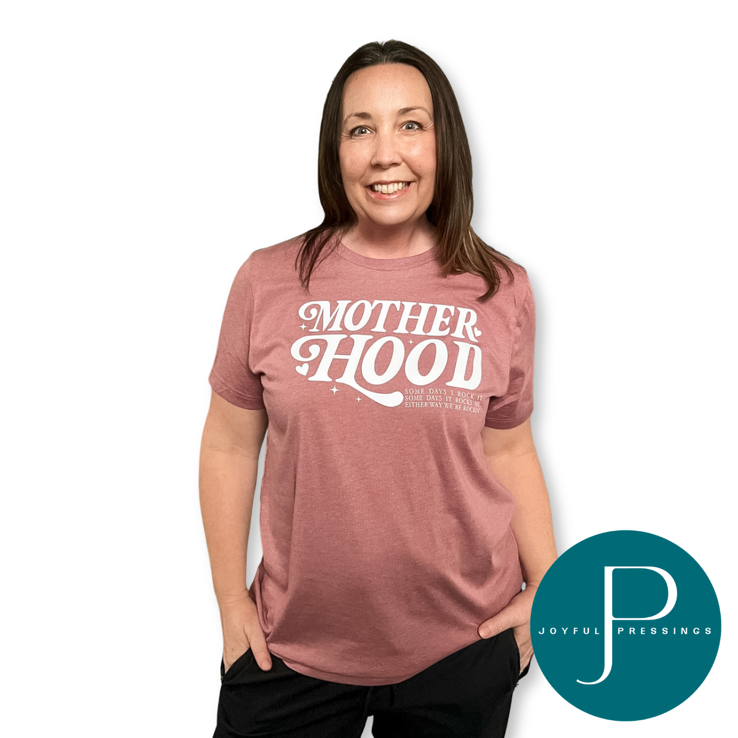 Woman wearing a t-shirt with 'MOTHERHOOD' text, standing against a white background with Joyful Pressings logo.