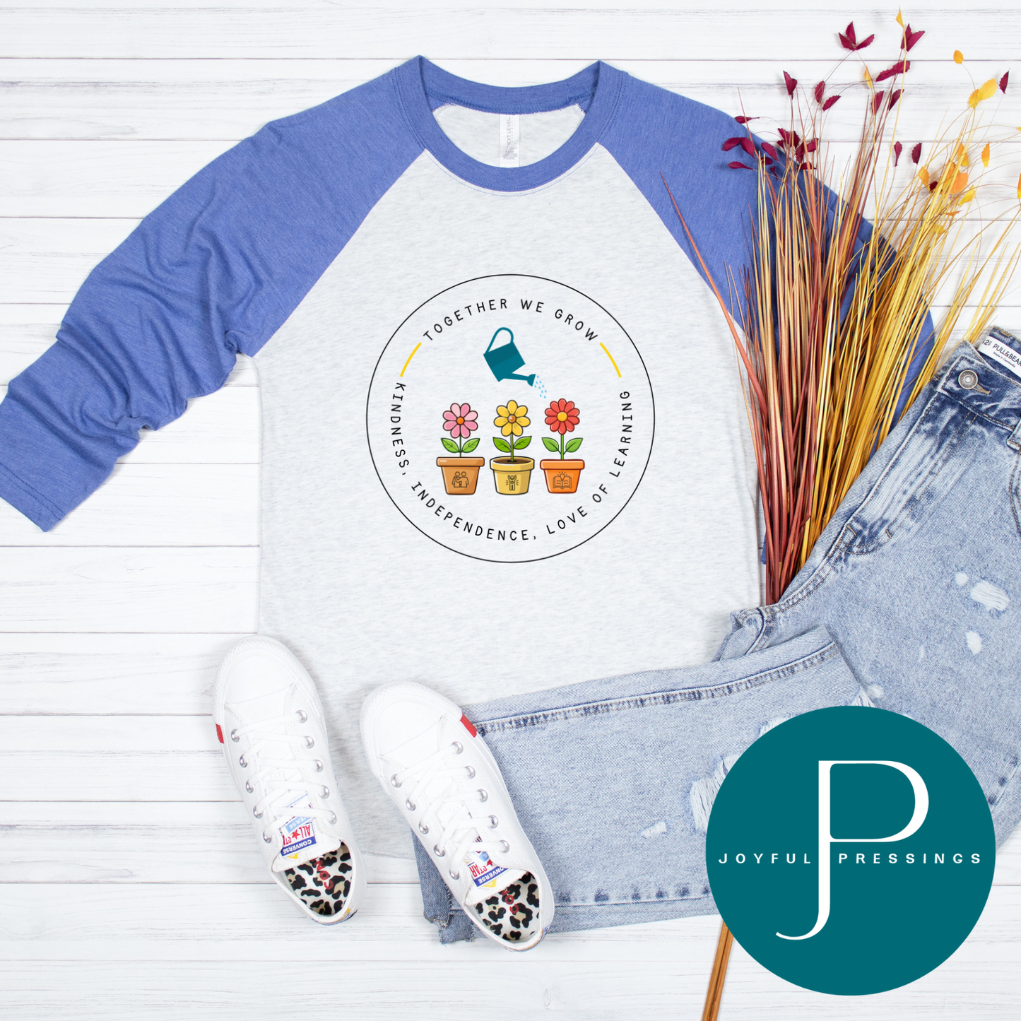 Blue and white baseball shirt with a logo, white sandals, and jeans on a wooden surface with 'Joyful Pressings' branding.