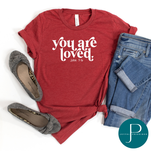 canvas red tee with you are loved in white in a flat mockup