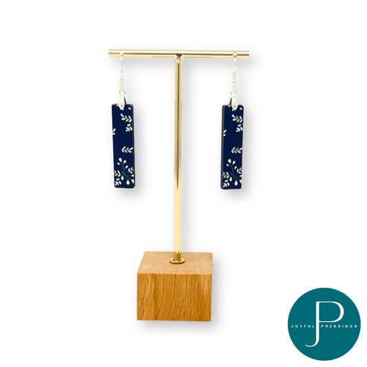 Black & white holly branch bar earrings on a display