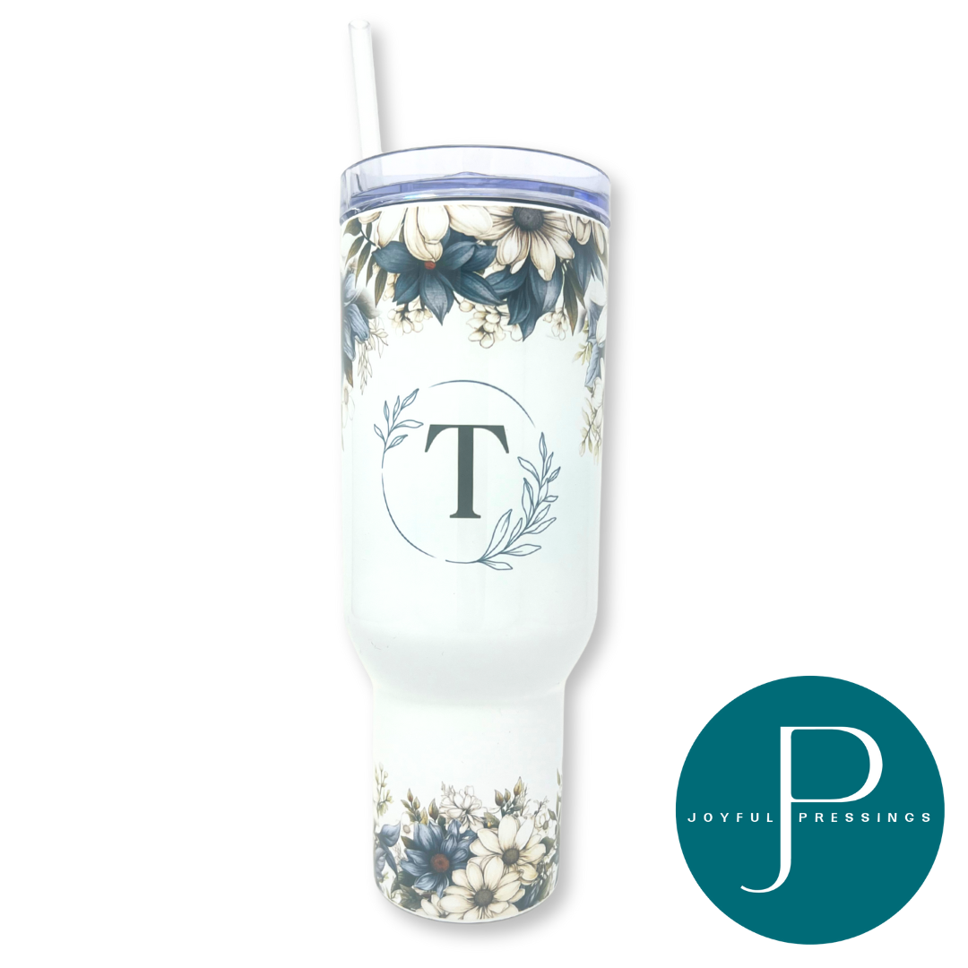 White tumbler with floral design and letter 'T' on a white background, featuring the 'Joyful Pressings' logo.