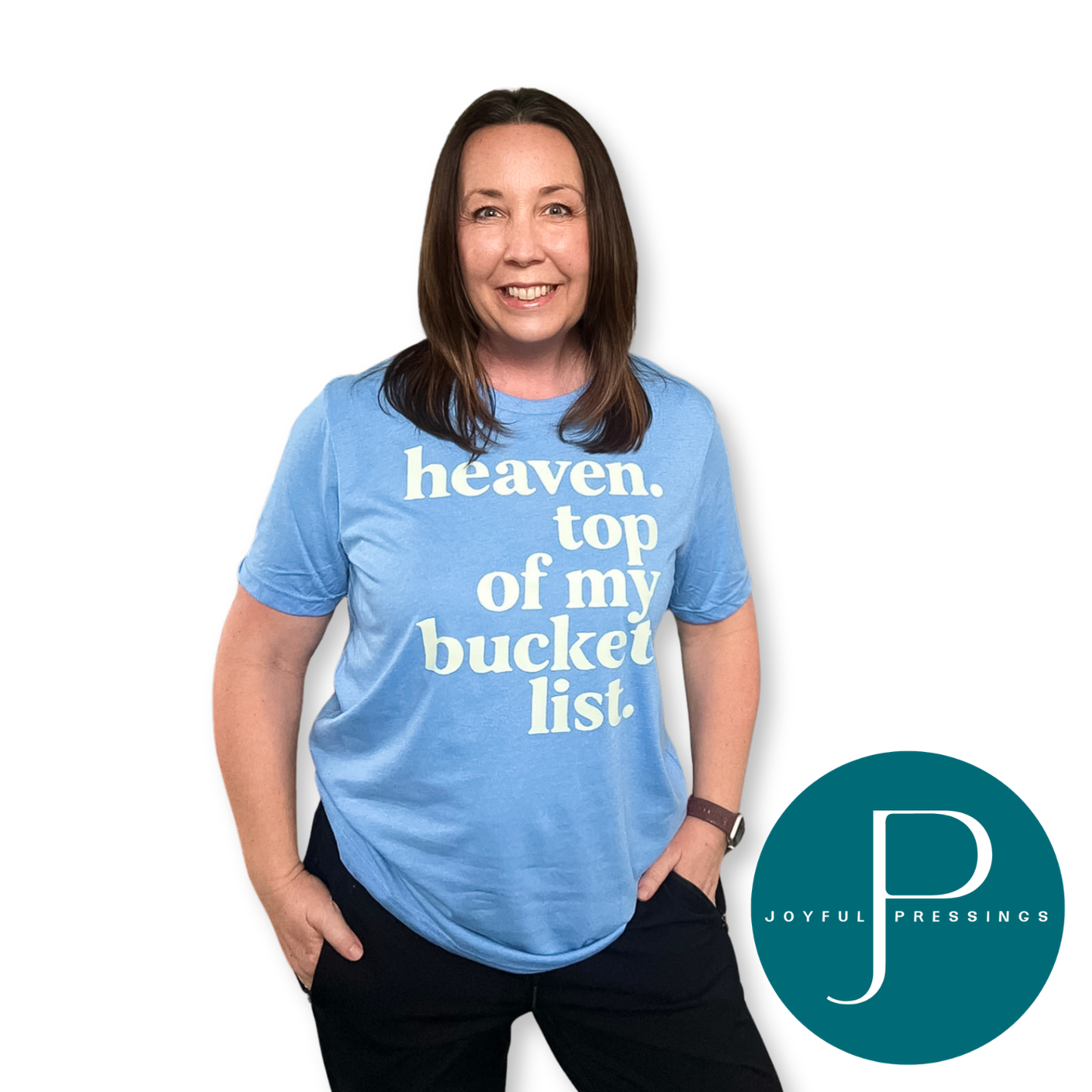 A woman wearing a light blue graphic t-shirt with the text 'heaven. top of my bucket list.
