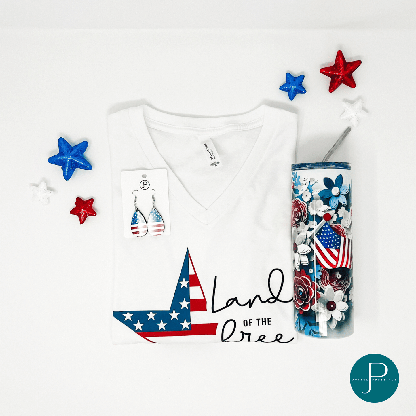 flat mockup of land of the free white v-neck t-shirt with matching earrings and tumbler