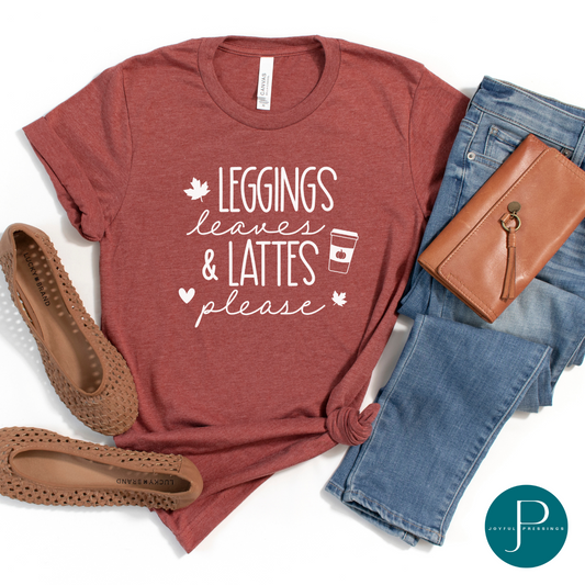 Flat-lay of heather clay t-shirt with the print Leggings Leaves & Lattes please in white.