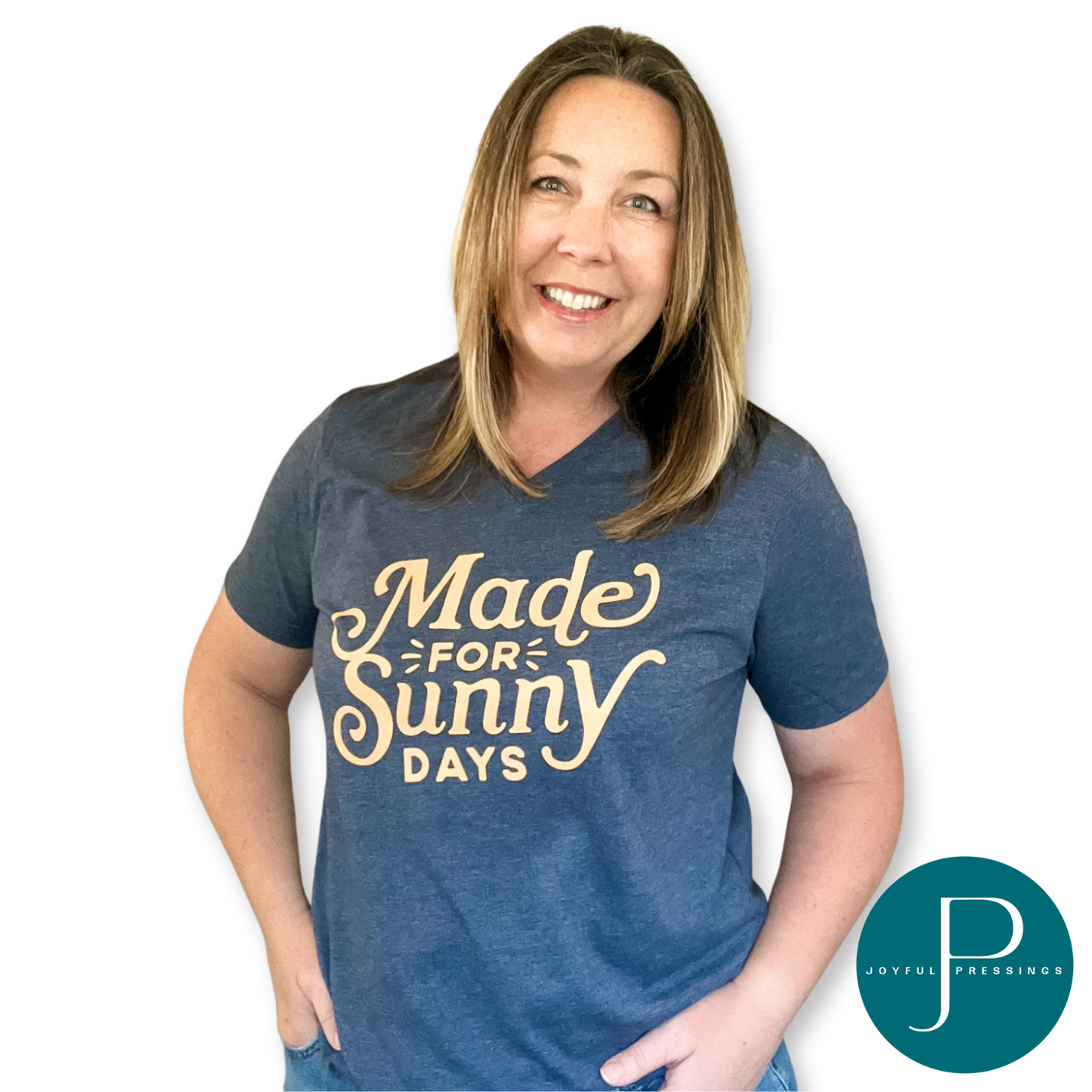 Woman wearing a heather navy v-neck t-shirt with the phrase "Made for Sunny Days" in yellow lettering, smiling with hands in her pocket.