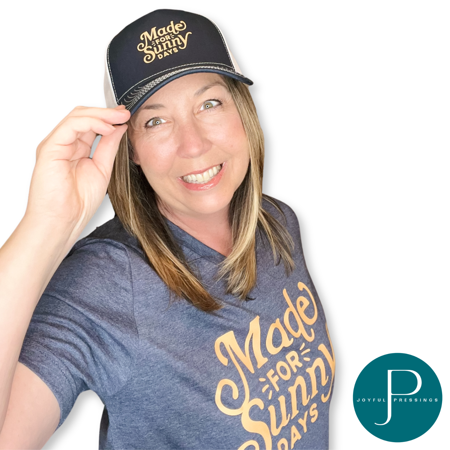 Woman smiling and touching the brim of a navy and white trucker hat that says "Made for Sunny Days," wearing a matching heather navy t-shirt.