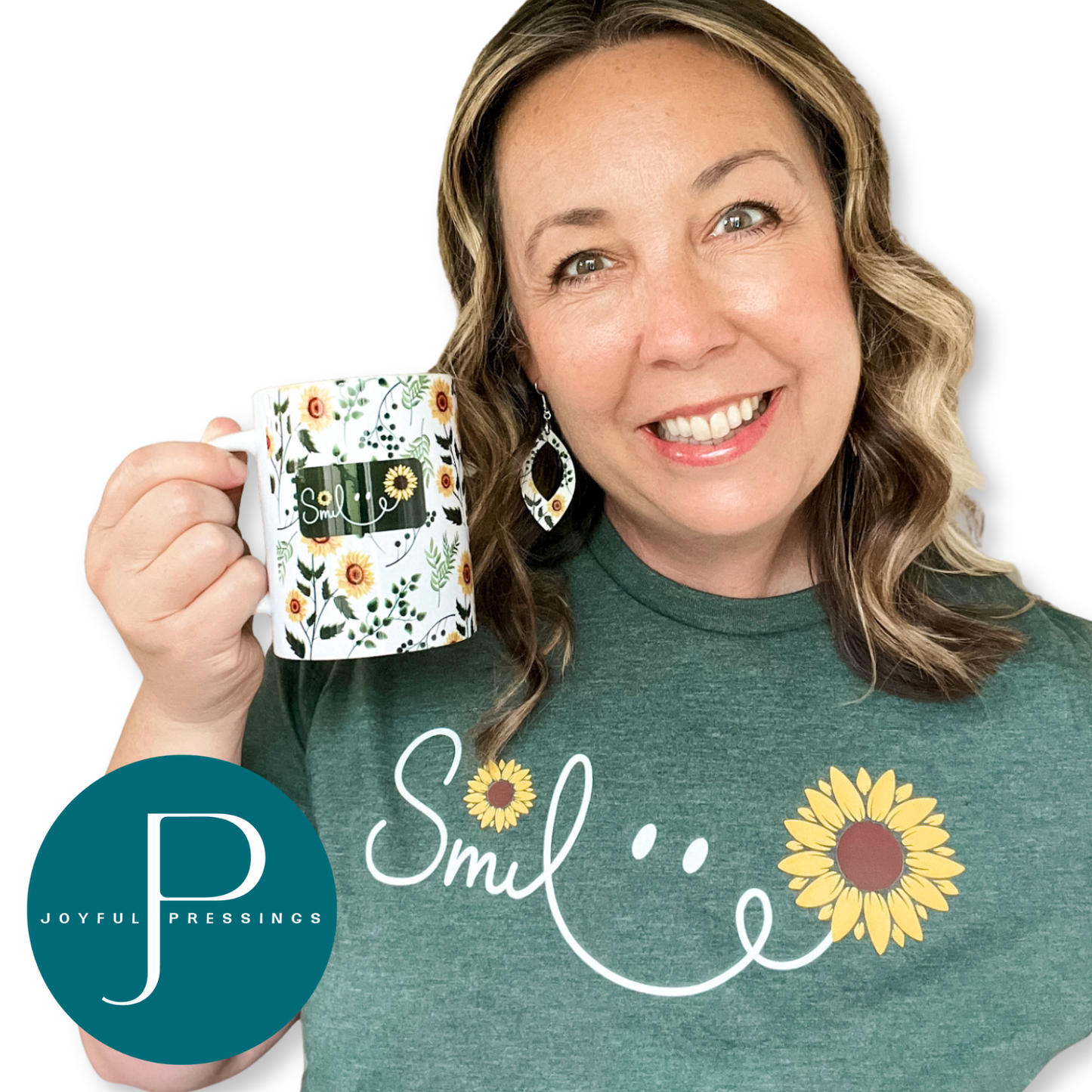 Smiling woman wearing a green t-shirt with a sunflower ‘Smile’ design and matching sunflower earrings, holding a coordinating sunflower mug.