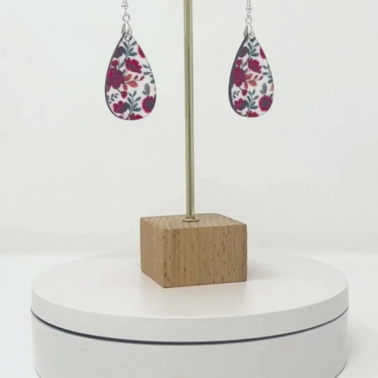 Video of red teardrop earrings circling around on pedestal.