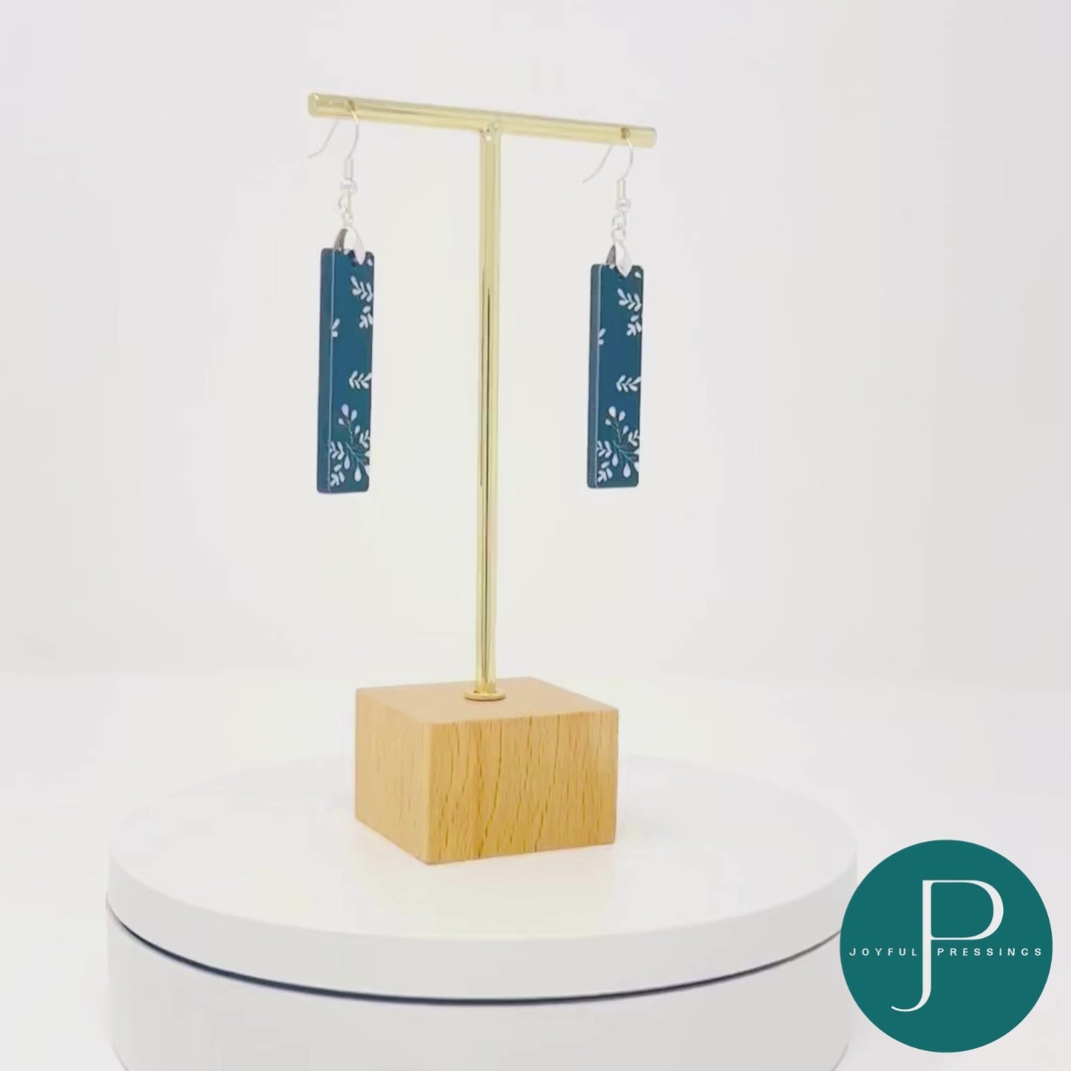 Black & white holly branch bar earrings rotating in a video.