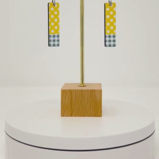 video showcasing yellow and white polka dot earrings with grey plaid.