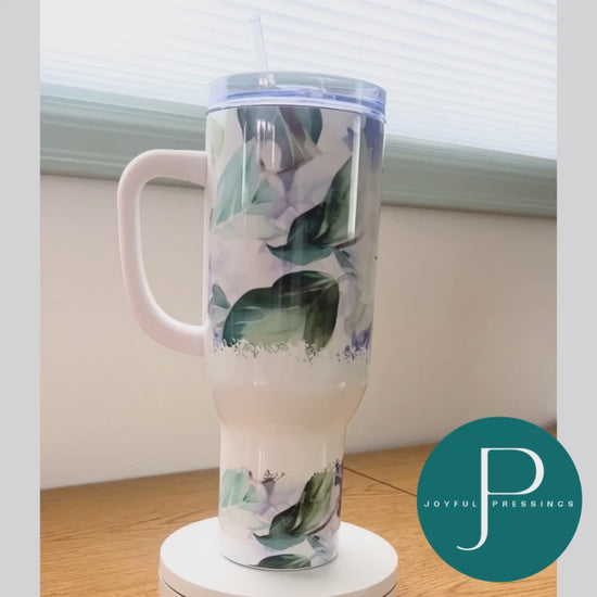A white, purple and green floral 40 oz tumbler rotating around.
