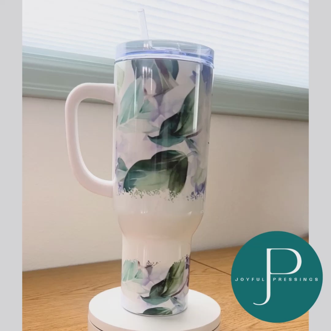 A white, purple and green floral 40 oz tumbler rotating around.