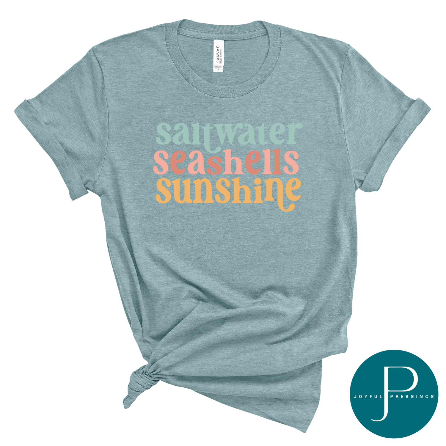 Heather blue lagoon t-shirt with the words "saltwater seashells sunshine" in mint green, coral, and golden yellow retro-style lettering; styled flat with a side knot.