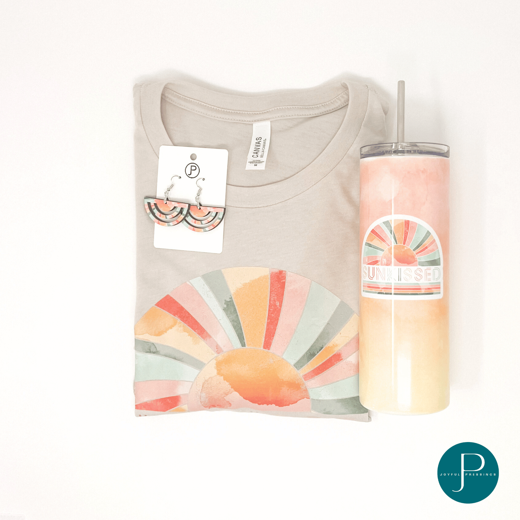 pink, teal and orange "sunkissed" print on a tan tee paired with matching earrings and tumbler